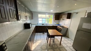 A kitchen with a patterned tile floor, a wooden table, and a refrigerator. - Villa 126 (Dubai)