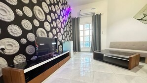 A modern living room with a black and white patterned wall, a flat-screen TV, a sofa, and a coffee table. - Villa 126 (Dubai)