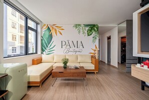Ein modernes Wohnzimmer mit einer Couch, einem Couchtisch und einer Wand mit einem tropischen Blatt-Wandbild.