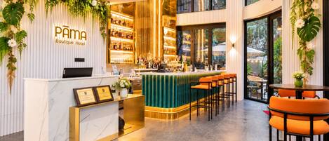 Zona de recepción de un hotel boutique con mostrador de mármol, bar y área de estar.