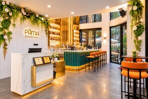 L’espace d’accueil d’un hôtel-boutique, doté d’un comptoir en marbre, d’un bar et d’un coin salon.