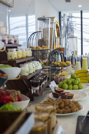 Een buffet met diverse gerechten en drankjes, waaronder fruit, gebak en zuivelproducten.