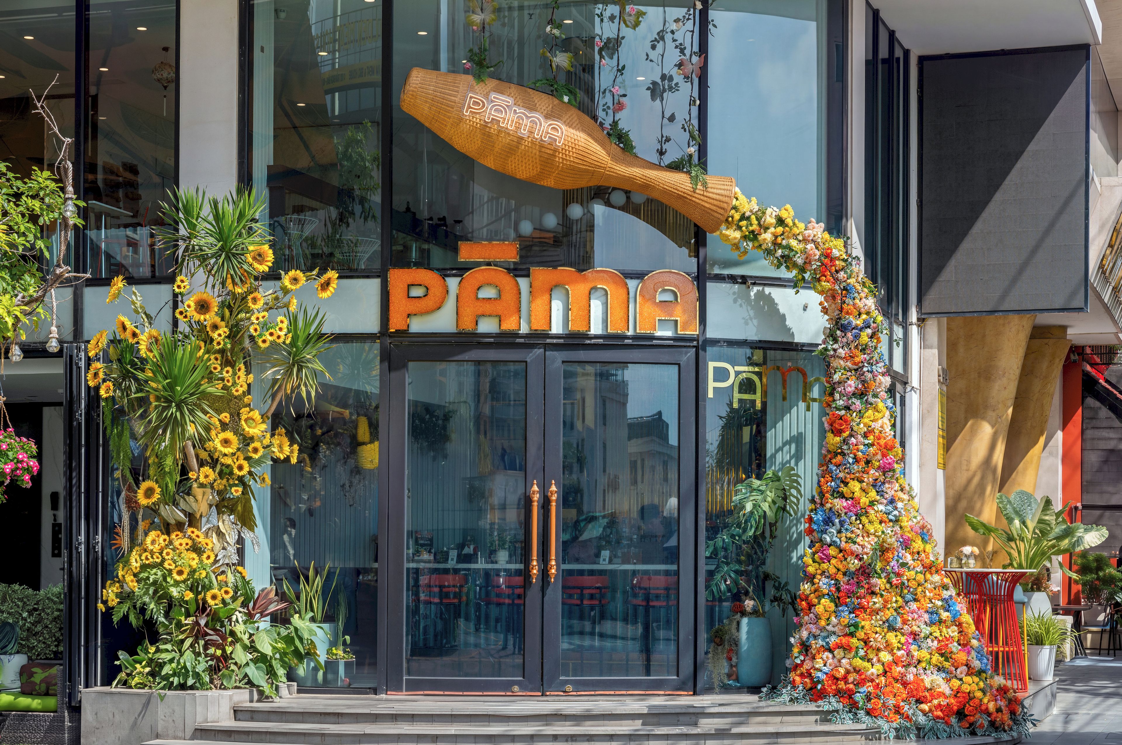 Fachada con un letrero grande que dice 'PAMA' y un arco decorativo de flores.