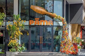 Une devanture de magasin avec une grande enseigne portant l’inscription « PAMA » et une arche décorative ornée de fleurs.