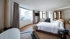 Una habitación de hotel moderna con una cama grande, un escritorio y vistas a la ciudad.