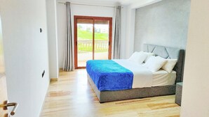 Un dormitorio con una cama, vista a través de un ventanal y suelo de madera.