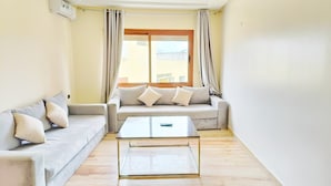 Una sala de estar con un sofá, una mesa de centro y una ventana con cortinas.