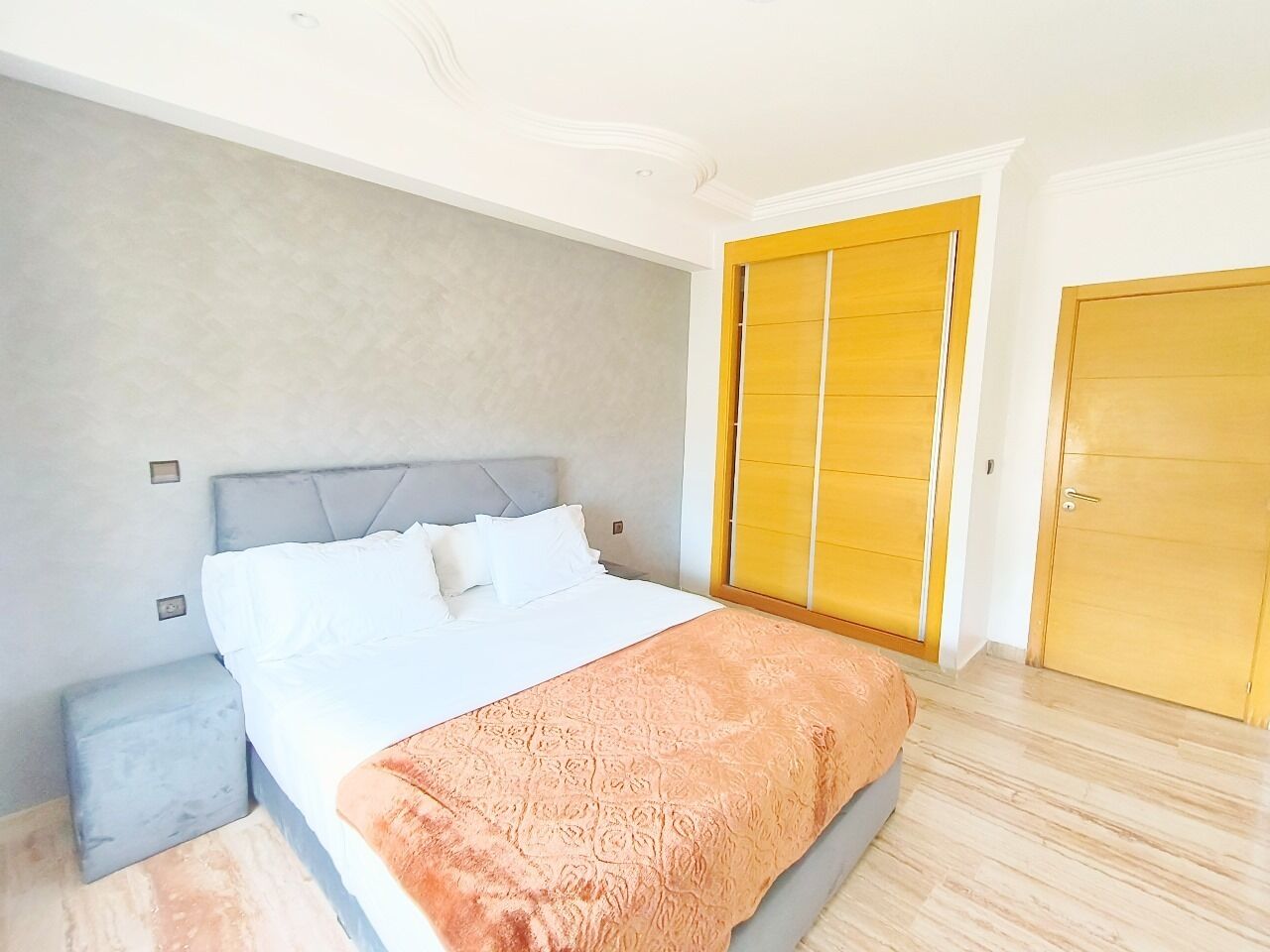 Une chambre à coucher avec un lit, une table de chevet, une armoire et une porte.