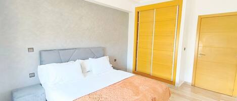 Une chambre à coucher avec un lit, une table de chevet, une armoire et une porte.