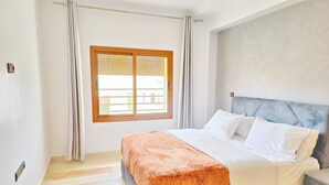 Un dormitorio con cama, ventana y vistas al exterior.