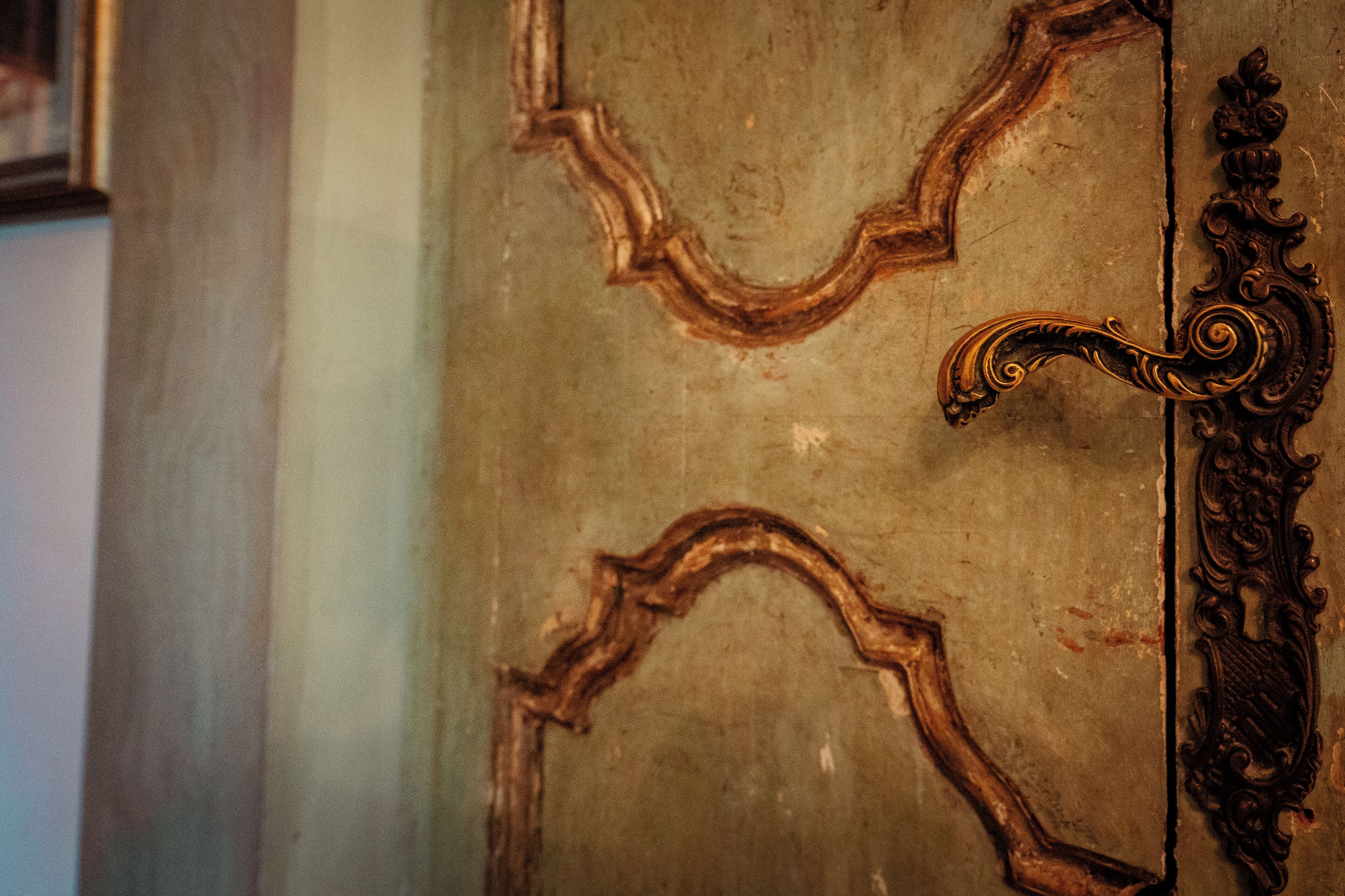 Un primo piano di una porta con maniglie in metallo ornate e intagli decorative.