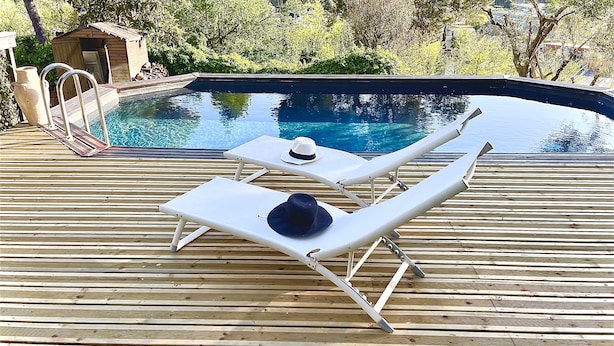 Une terrasse en bois avec deux chaises longues et une piscine.