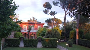 Un bâtiment rouge doté d’une cour intérieure, entouré de haies et d’arbres bien entretenus.