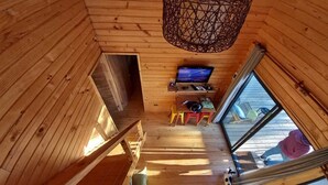 L’intérieur d’une cabane en bois, avec une télévision, une petite table et une fenêtre.