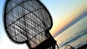 Ein Strandstuhl mit Metallgestell und Gewebesitz, platziert auf einer Tischdecke mit Schildmuster.