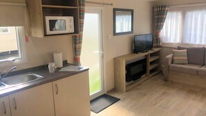 A compact living space with a kitchenette, a television, and a sofa.