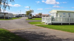 A caravan park with multiple caravans, a grassy area, and a paved road.