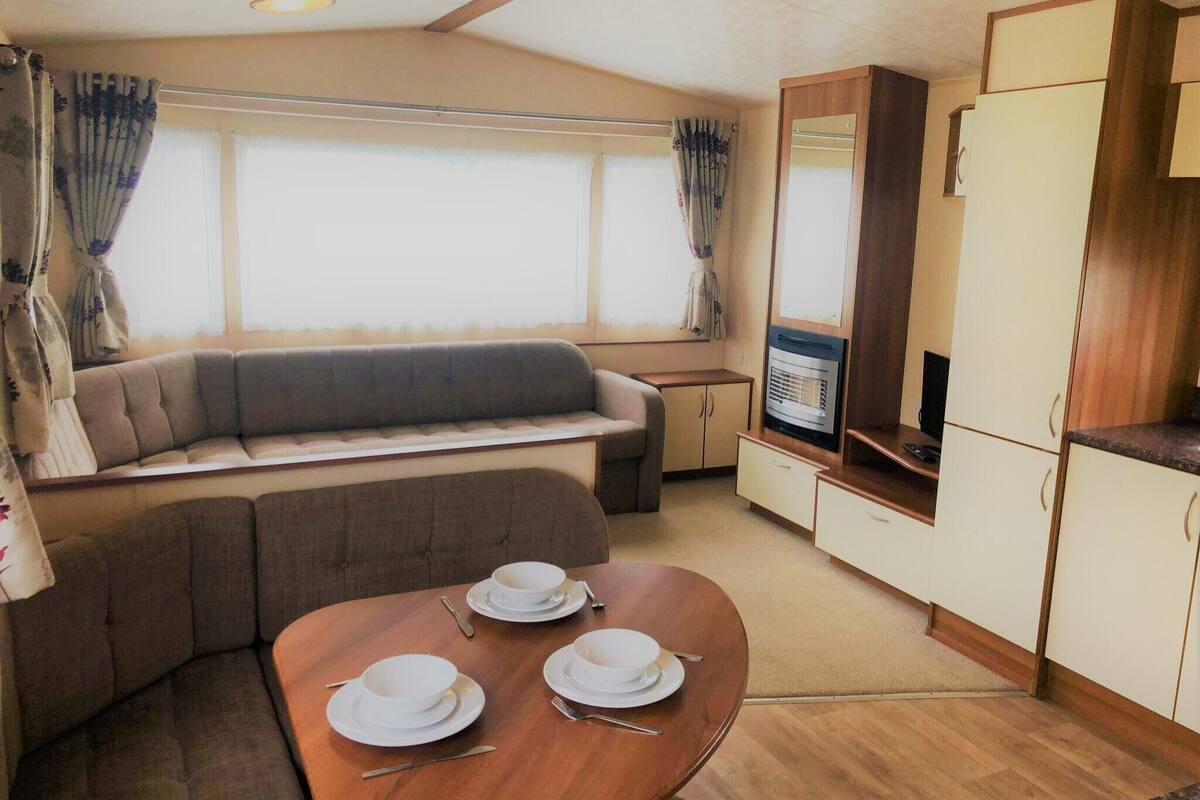 A compact living space with a sofa, a dining table set with plates and cutlery, a television, and cabinets.