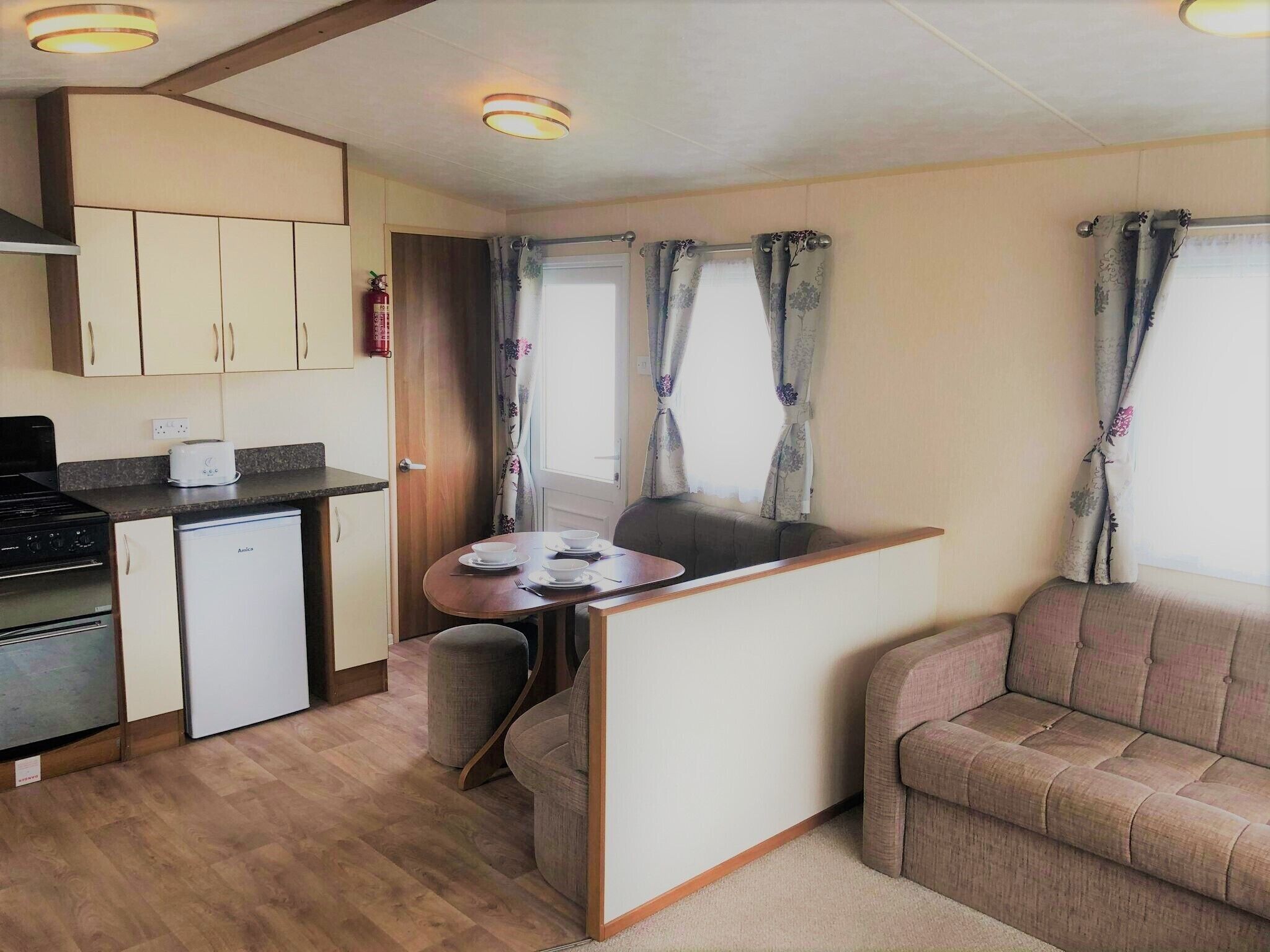 A compact kitchenette with a stove, a small fridge, and a dining area with a table and two chairs.