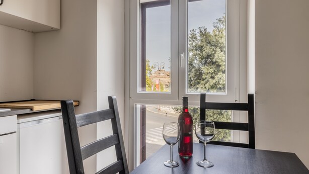 Ein Essbereich mit Tisch, Stühlen, einer Flasche Rotwein und zwei Weingläsern.