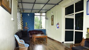 A living room with a brown leather sofa, a blue patterned couch, a wooden coffee table, and wicker chairs.