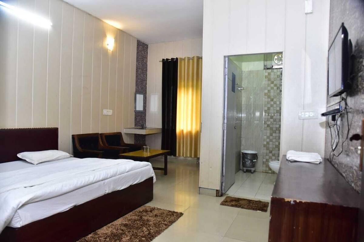 Une chambre d’hôtel équipée d’un lit, d’un bureau, d’une chaise, d’une télévision et d’une salle de bain avec douche et toilettes.