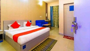 A hotel room with a large bed, a desk, a chair, and a bathroom door.