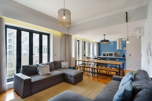 A modern living room with a sectional sofa, a dining table, and a kitchen area. - Feel Porto Elegant Townhouse (Oporto)
