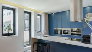 Een moderne keuken met een centraal kookeiland, barstoelen, een spoelbak en inbouwovens.