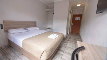 Una habitación de hotel con una cama, una silla, un televisor y una puerta.