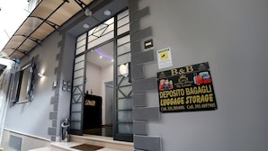 A building with a sign for B&B, a luggage storage area, and a staircase leading to the entrance. - My Luxury (Naples)