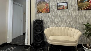 A modern lobby with a marble floor, a beige armchair, and three framed pictures on the wall. - My Luxury (Naples)