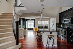 A spacious kitchen with a central island, dark cabinetry, and a wooden floor.