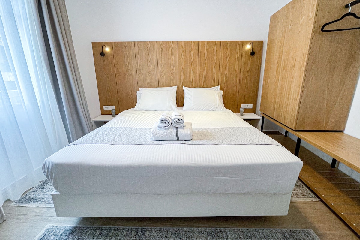 Une chambre d’hôtel avec un grand lit, une tête de lit en bois, des tables de chevet et une armoire.