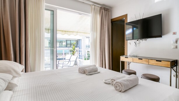 Une chambre d’hôtel avec un lit, une télévision, un bureau et un balcon donnant sur une vue agréable.