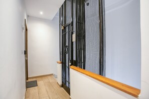 A narrow hallway with a wooden floor, a metal gate, and a white wall. - Elia Kolonaki Luxury Apartments  (Athens)
