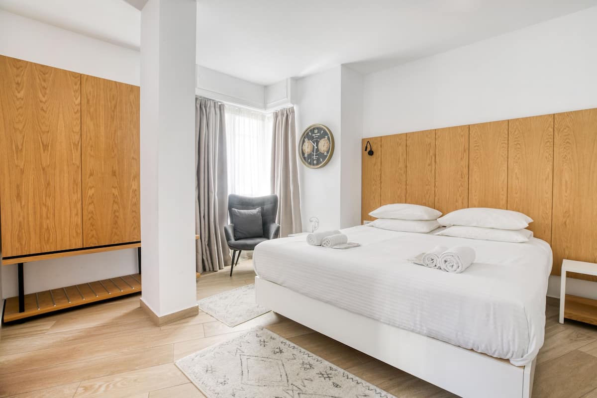 Une chambre à coucher moderne avec un grand lit, une armoire en bois et une chaise.