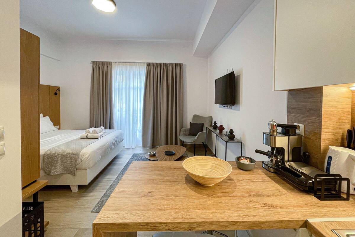 Une chambre d’hôtel comprenant un lit, une table à manger en bois, un téléviseur et une kitchenette.