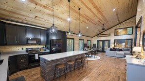 A spacious kitchen with dark cabinets, a large island with stools, and a wooden ceiling. - Ride to ATV Trails + Dog Run + Game Room + Bunk Bed Nook + Guests Favorite (Broken Bow)