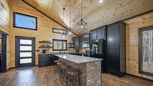 A modern kitchen with a central island, bar stools, and built-in appliances. - Ride to ATV Trails + Dog Run + Game Room + Bunk Bed Nook + Guests Favorite (Broken Bow)