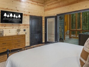 Ein Schlafzimmer in einer Holzhütte mit Bett, Kommode und einem Schild mit der Aufschrift 'BOOK BROKEN BOW LUXURY CABIN RENTALS'.