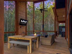 Eine Holzterrasse mit Tisch, Stühlen, einer Couch und einem Deckenventilator.