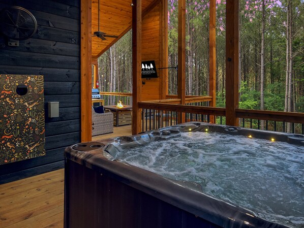 Ein Whirlpool in einer Blockhütte mit Blick auf einen Wald.