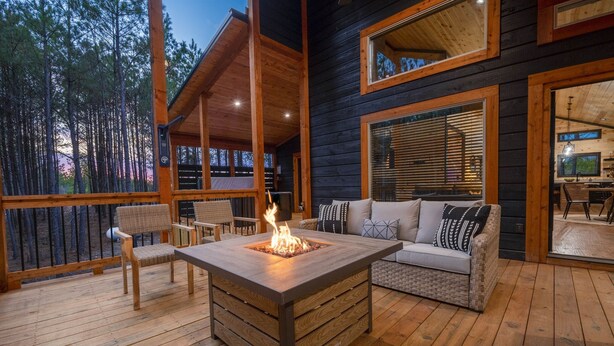 A wooden deck with a fire pit, outdoor seating, and a view of a forest. - Ride to ATV Trails + Dog Run + Game Room + Bunk Bed Nook + Guests Favorite (Broken Bow)