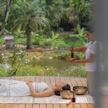 A person lying on a mat outdoors, holding a bowl.