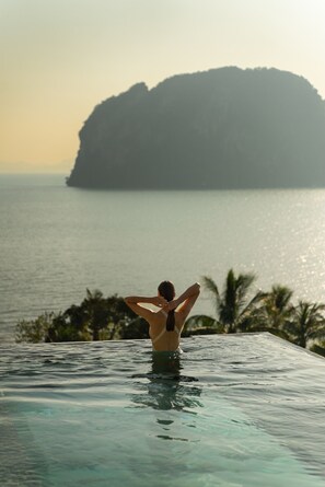 Una persona en una piscina con vista a una isla grande y al mar.