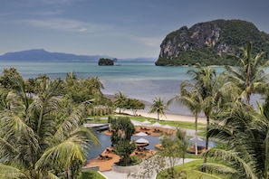 Un resort con zona de piscina, sillones de descanso y vistas al mar y una isla grande.