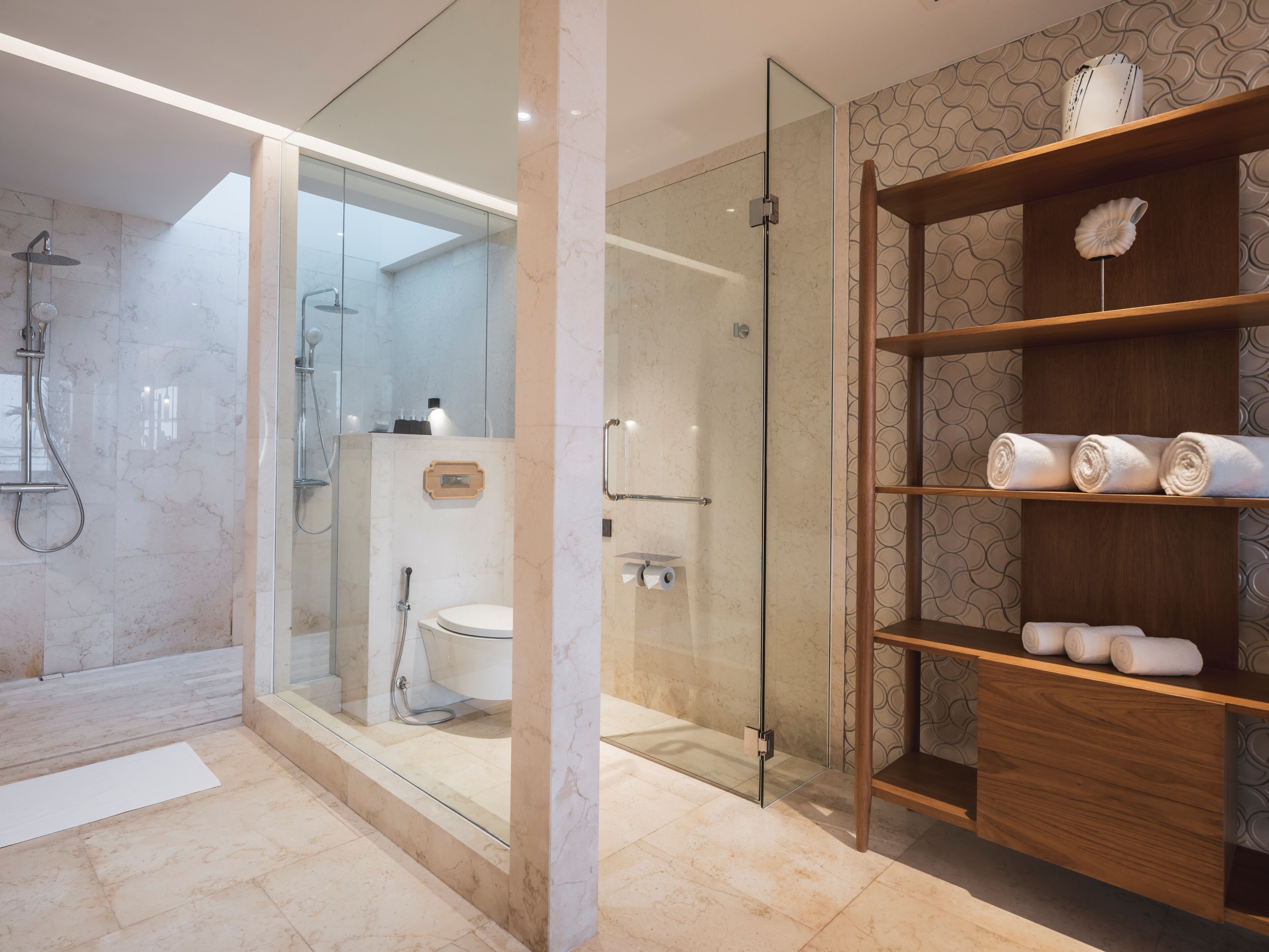 Une salle de bain moderne avec une douche à parois de verre, un meuble-lavabo en bois agrémenté de serviettes et un revêtement de sol en marbre.