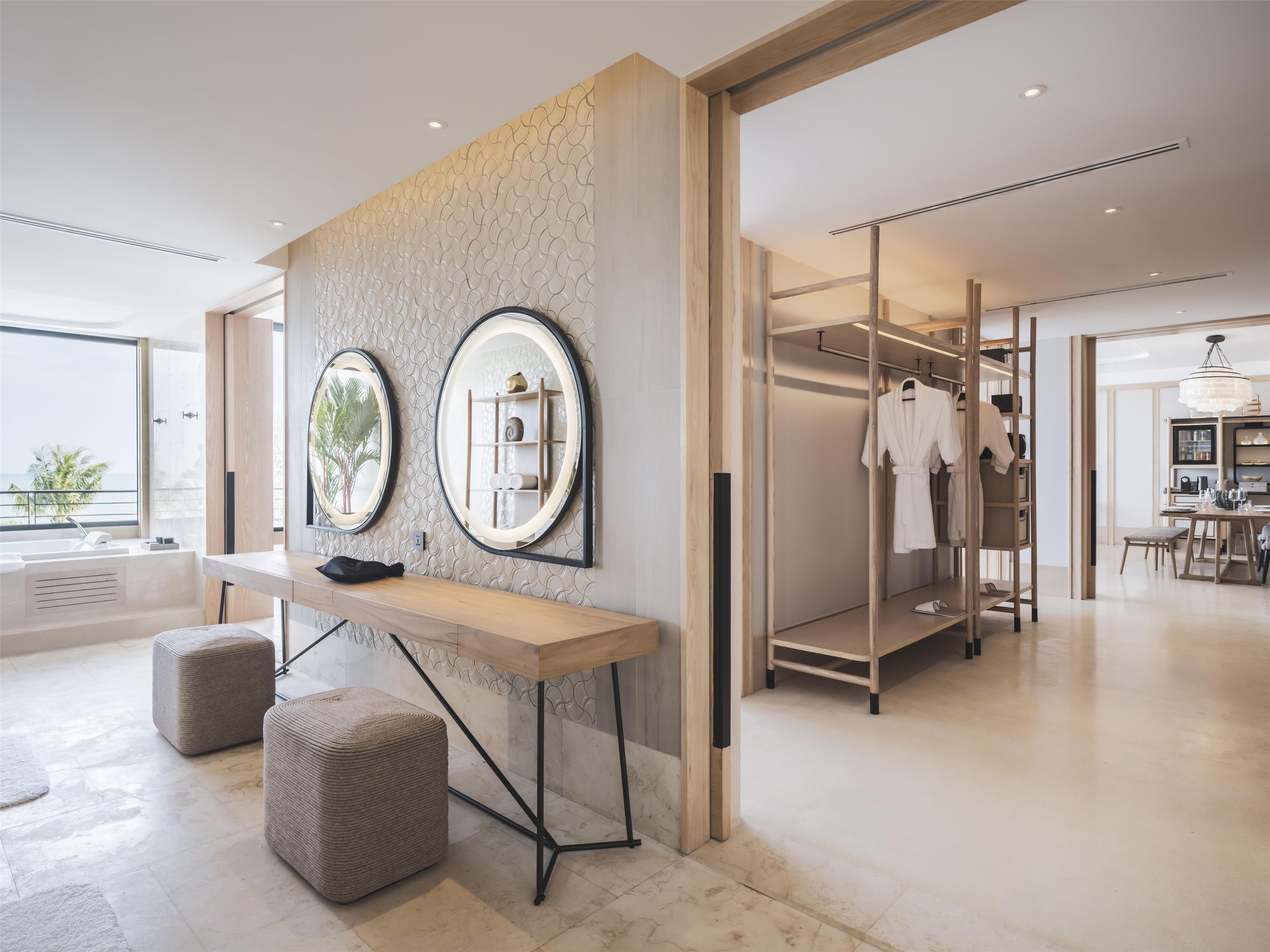 A modern bathroom with a vanity, two mirrors, and a view of the sea.