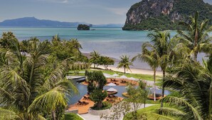 A resort with a pool area, palm trees, and a view of the sea and mountains. - Anantara Koh Yao Yai Resort & Villas (Ko Yao)
